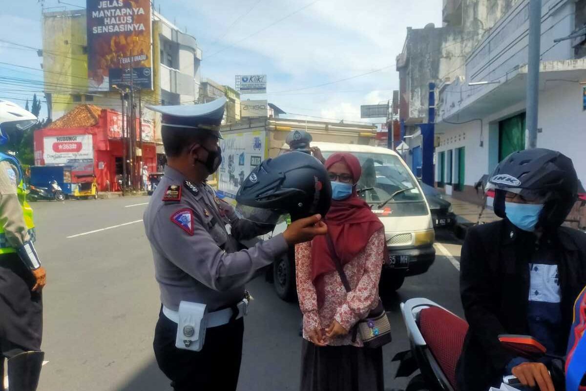 Petugas Lalu Lintas Polresta Tasikmalaya memberikan helm baru gratis kepada warga yang dinilai paling taat protokol kesehatan saat berkendara dalam Operasi Zebra di Jalan HZ Mustofa, Kota Tasikmalaya, Kamis (25/11/2021).