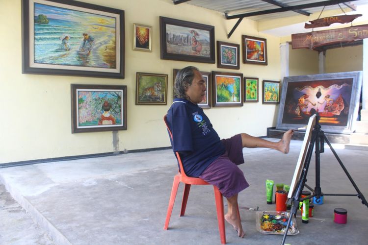Sadikin Pard saat melukis menggunakan kakinya di padepokannya di Jalan Selat Sunda Raya D1/40B Kota Malang, Selasa (16/10/2018)