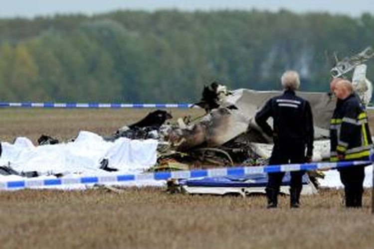Petugas pemadam kebakaran memperhatikan puing-puing pesawat terbang yang jatuh tak lama setelah tinggal landas di sebuah kota kecil di Belgia, menewaskan 11 orang di dalamnya.