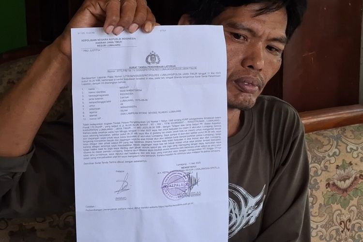 Misrat menunjukkan surat laporan pengeroyokan oknum Satpol PP Lumajang.