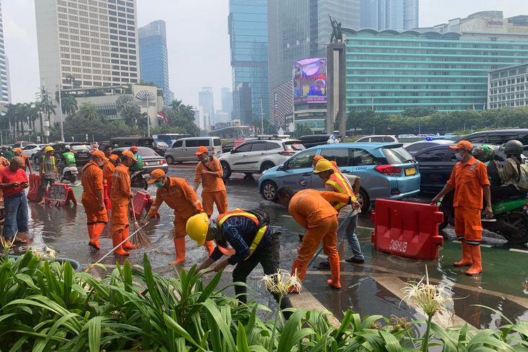 Petugas PPSU berusaha mengeringkan genangan air sekitar 40 cm yang diduga muncul akibat bocornya saluran pipa air di kawasan Bundaran HI, Jakarta Pusat, Selasa (11/10/2022). 