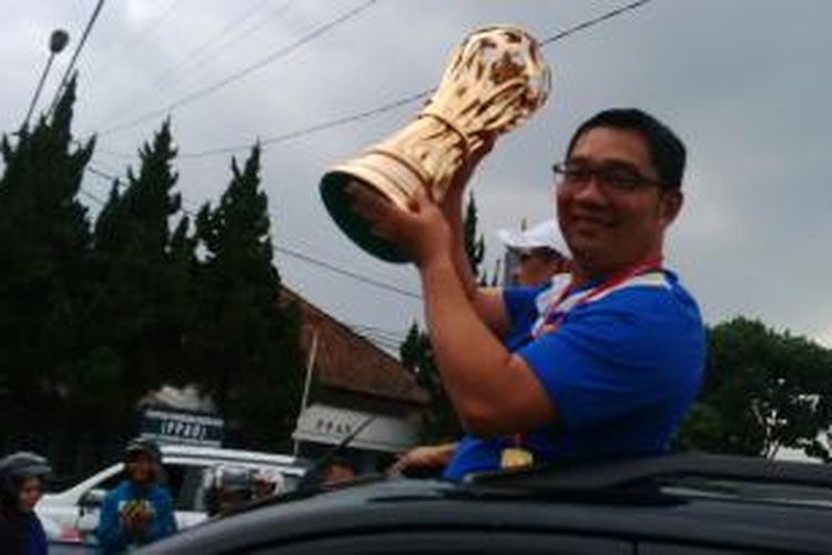Wali Kota Bandung Ridwan Kamil memegang piala kemenangan Persib saat melakukan arak - arakan dengan ribuan bobotoh mengelilingi Kota Bandung, Sabtu, (8/11/2014).