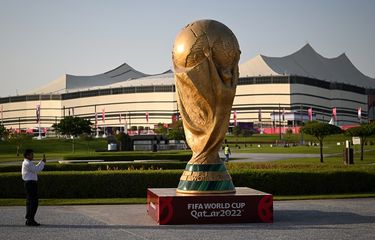 Seorang pria mengambil gambar replika trofi Piala Dunia FIFA di depan Stadion Al-Bayt di al-Khor pada 10 November 2022, menjelang turnamen sepak bola Piala Dunia 2022 Qatar. Piala Dunia 2022 dibuka dengan laga Qatar vs Ekuador pada Minggu (20/11/2022) malam WIB.