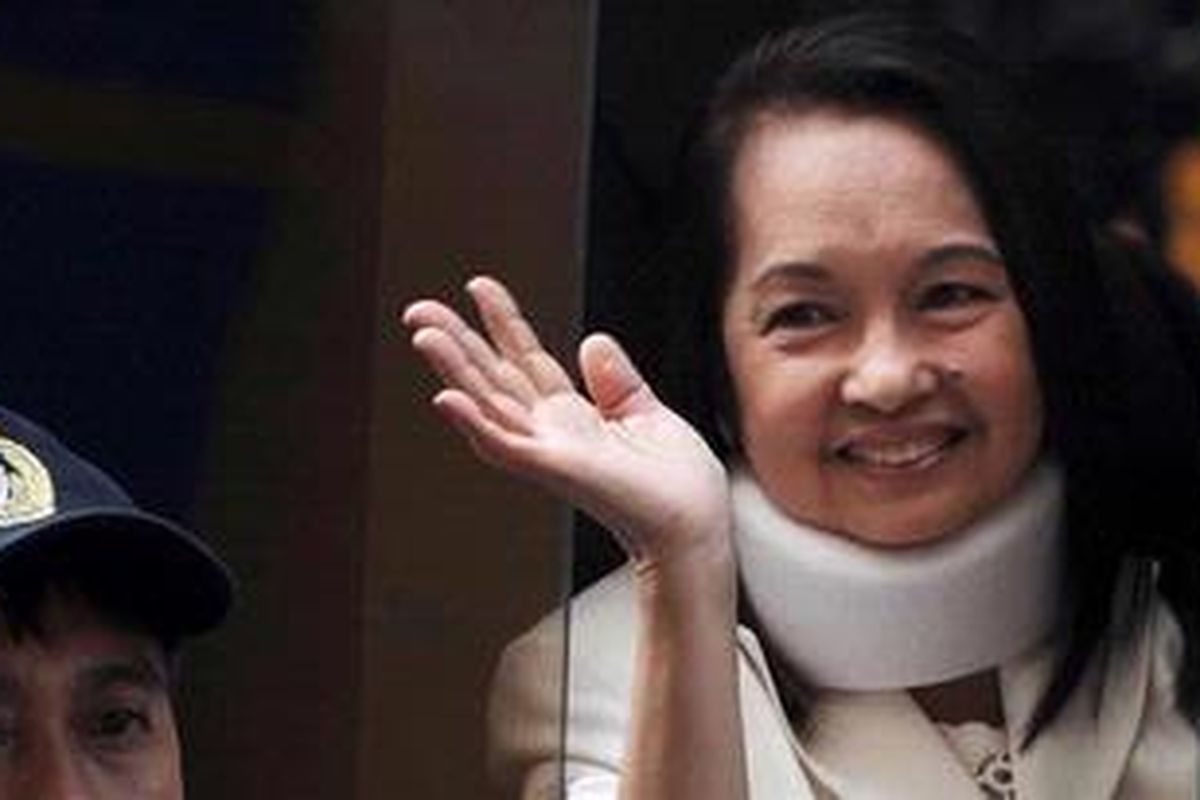 Mantan Presiden Filipina Gloria Macapagal Arroyo melambaikan tangan ke arah para fotografer dari dalam mobil yang membawanya usai menghadiri persidangan di Manila, Kamis (23/2/2012). 