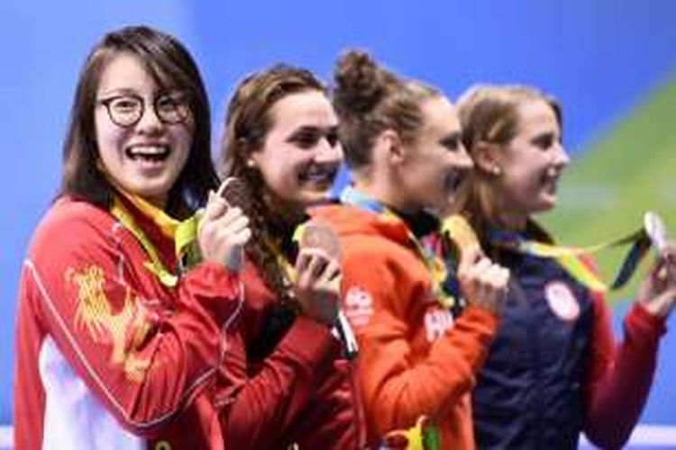 Perenang putri asal China, Fu Yuanhui, tertawa lepas sambil memamerkan medali perunggu yang diperolehnya dari nomor 100 meter gaya punggung di Olympic Aquatics Stadium, Rio de Janeiro, Senin (8/8/2016). 