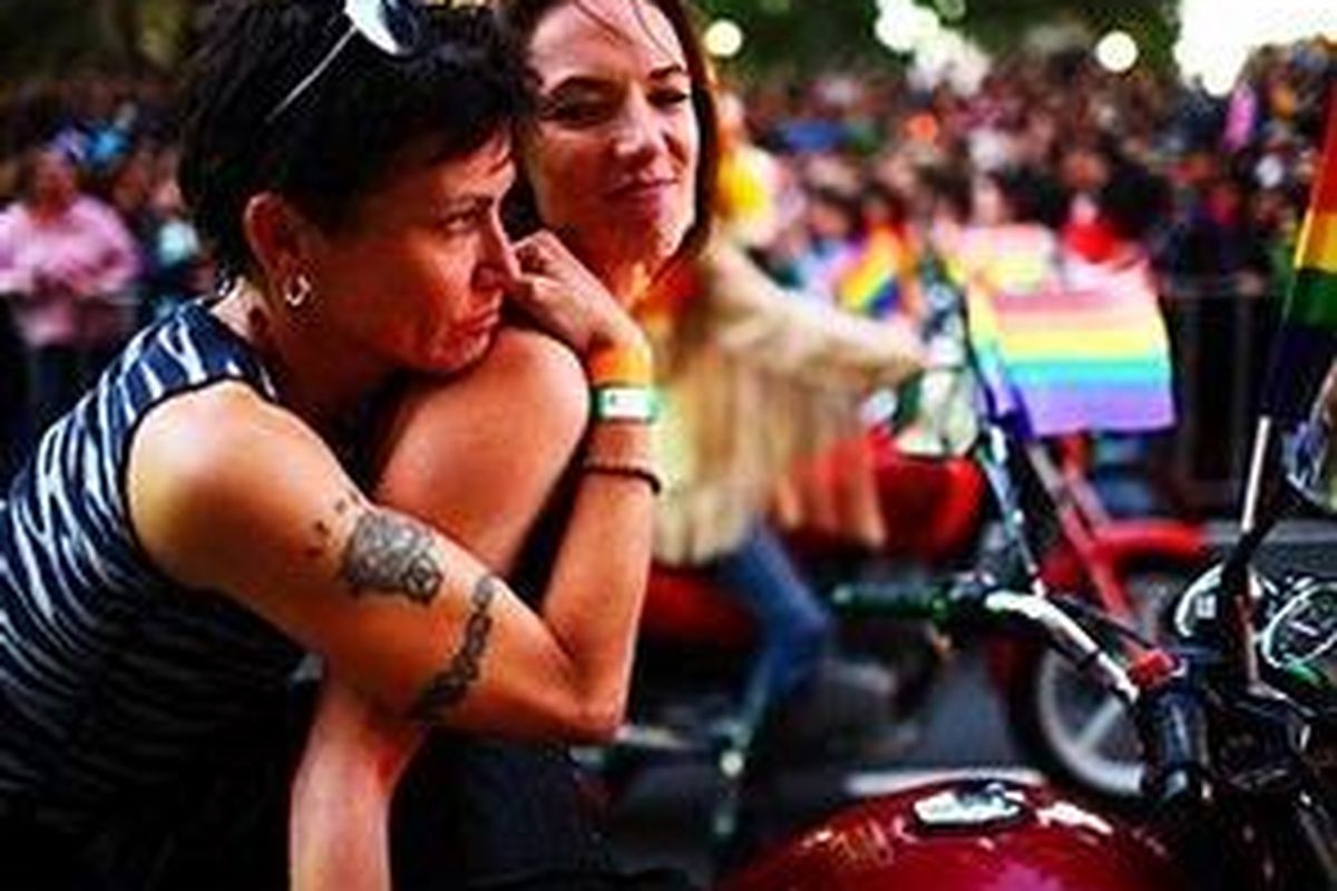 Ilustrasi:Sepasang lesbian berpelukan dalam sebuah parade di Sydney.