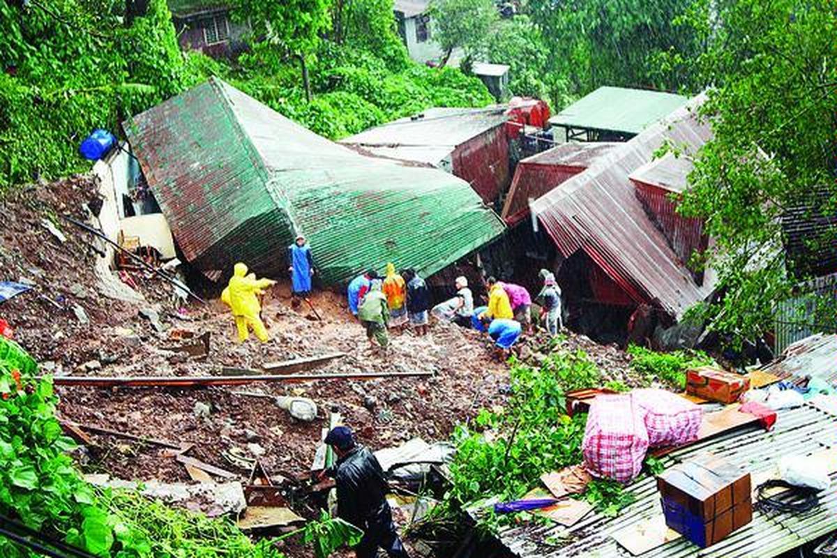 Petugas penyelamat mencoba menggali untuk menemukan warga yang terjebak di dalam rumah-rumah yang ambruk akibat longsor, di Desa Cresencia, Baguio, Filipina utara, Jumat (9/10).