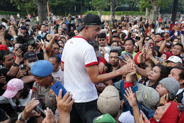 Gubernur Jawa Tengah sekaligus bakal calon presiden yang diusung Partai Demokrasi Indonesia Perjuangan, Ganjar Pranowo menyapa simpatisan saat lari pagi di kawasan Stadion Gelora Bung Karno, Jakarta, Minggu (30/4/2023).