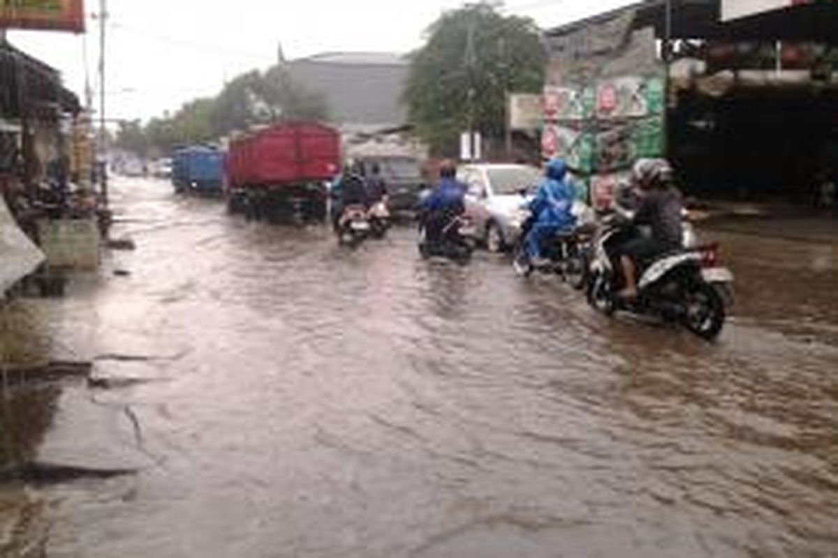 Hujan deras yang mengguyur kota Tangerang Selatan dan menutup jalan berlubang sangat mebahayakan pengguna jalan, Senin (14/4/2014).