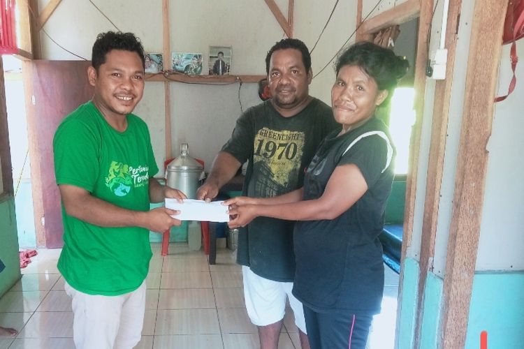 Jurnalis Kompas.com (kiri) menyerahkan donasi pembaca Kompas.com kepada Anastasia Sao di rumahnya di Dusun Mageloo, Desa Reroroja, Kabupaten Sikka, Minggu (17/12/2023).