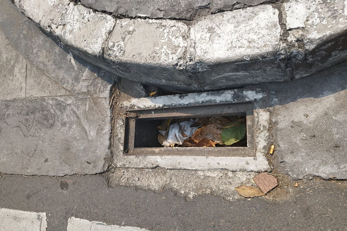 Sampah memenuhi salah satu saluran air dengan besi grill yang hilang di Jalan Cikini Raya, Menteng, Jakarta Pusat, Selasa (15/8/2023). (KOMPAS.com/XENA OLIVIA)
