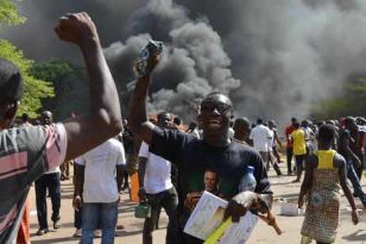 Pengunjuk rasa bersorak sorai di luar gedung parlemen Burkina Faso di ibu kota Ouagadougou yang terbakar, Kamis (30/10/2014).