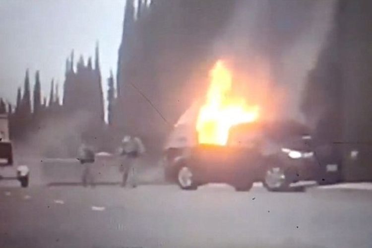 Petugas berusaha memadamkan api yang membakar sebuah mobil yang digunakan pelaku teror menerobos pangkalan udara di California utara.