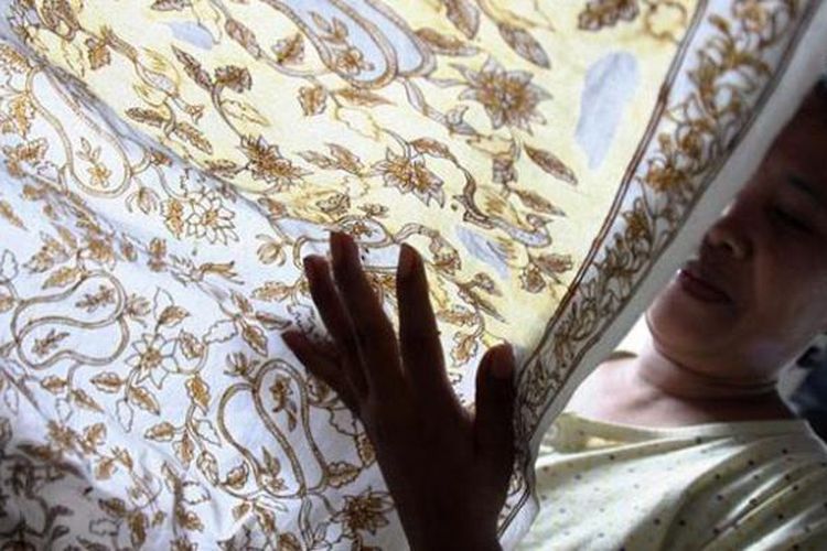 Perajin batik Lasem sedang ngeblok atau menutup bagian kain menggunakan malam.