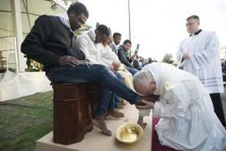 Paus Fransiskus mencium kaki seorang pria saat ritual membasuh kaki di pusat migran Castelnuovo di Porto dekat Roma, saat Kamis Putih (24/3/2016)