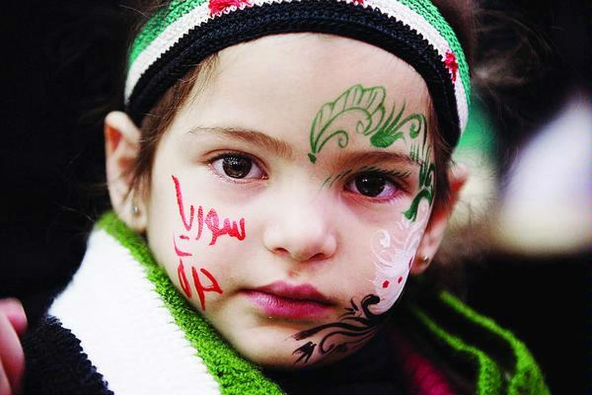 Seorang anak perempuan Yaman,  yang wajahnya dilukis dengan warna-warna bendera revolusi Suriah dan tulisan berbahasa Arab berbunyi 