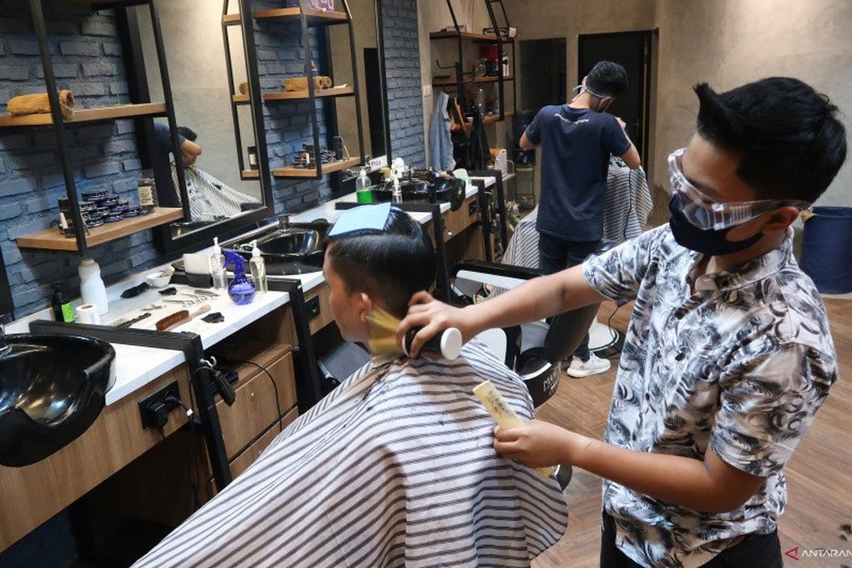 Seorang kapster sedang mencukur rambut pelanggan di Mancave Barbershop di Pasar Baru, Jakarta Pusat, Rabu (17/6/2020). Dia menggunakan alat pelindung diri berupa masker dan kacamata goggle saat bekerja untuk mencegah penularan virus COVID-19.