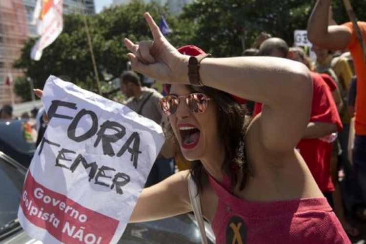 Seorang demonstran memegang kertas bertuliskan Temer Keluar (Fora Temer) dalam protes melawan Presiden Brazil Michel Temer di pantai Copacabana beach, Rio de Janeiro, Brasil, Minggu (4/9/2016) atau Senin (5/9/2016)