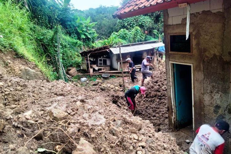 Warga berupaya membersihkan material longsor berupa tanah dan bebatuan yang menimbun sebuah rumah di Kabupaten Cianjur, Jawa Barat, Minggu (6/11/2022).
