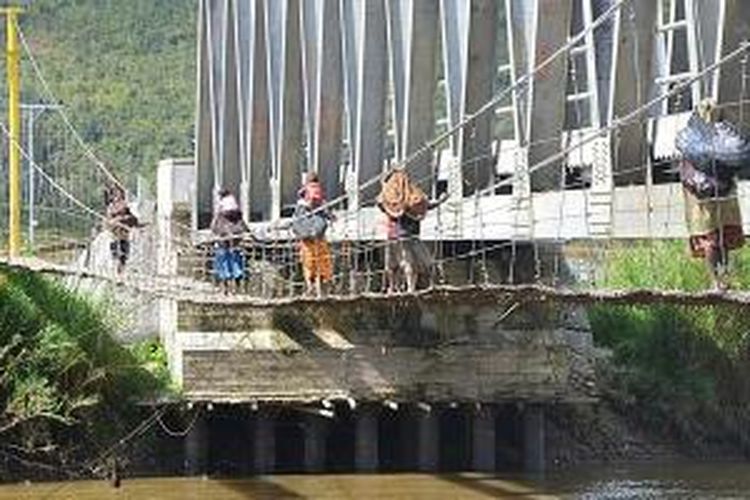 Sejumlah masyarakat asli Lembah Baliem melewati jembatan gantung Sungai Baliem di Wamena, Kabupaten Jayawijaya, Provinsi Papua, beberapa waktu lalu. Untuk menghubungkan antarwilayah yang terpisah oleh sungai, jurang, dan bukit, pemerintah pusat membangun jembatan dan jalan di Wamena. Pemerintah pusat mengalokasikan  dana pembangunan Papua dan Papua Barat pada 2013 sebesar Rp 52,1 triliun.