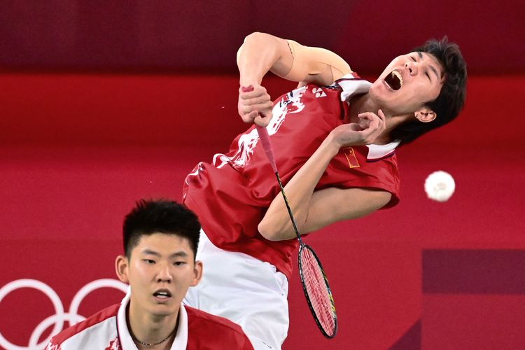 China's Li Junhui (R) hits a shot next to China's Liu Yuchen in their men's doubles badminton quarter final match against Denmark's Kim Astrup and Denmark's Anders Skaarup Rasmussen during the Tokyo 2020 Olympic Games at the Musashino Forest Sports Plaza in Tokyo on July 29, 2021. (Photo by Pedro PARDO / AFP)