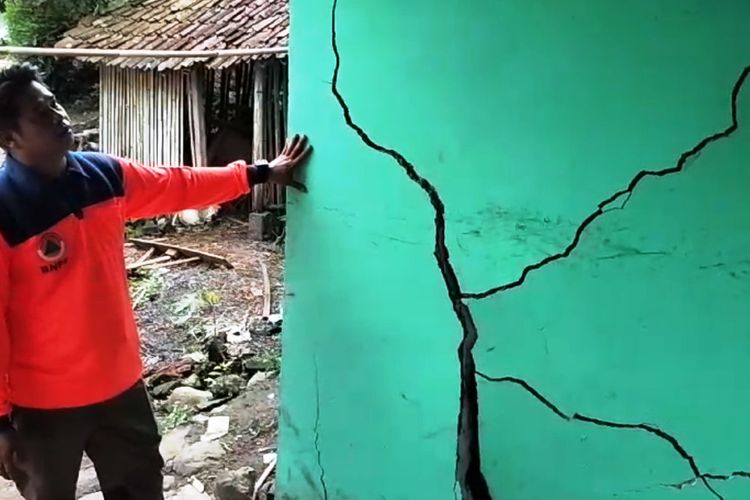 Seorang petugas BPBD memperlihatkan kondisi dinding rumah yang retak akibat pergerakan tanah di Desa Sukajadi, Desa Jatisari, Kecamatan Bojongpocung, Kabupaten Cianjur, Jawa Barat, Jumat *26/4/2024).