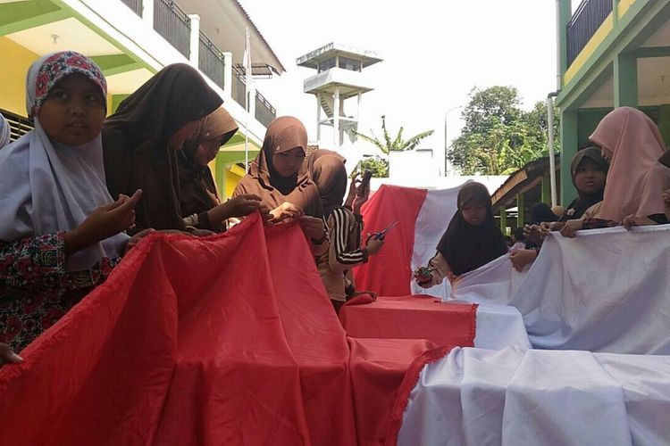 Para siswa SD Islam Terpadu (SDIT) Al Uswah Banyuwangi sedang menjahit bendera sepanjang 25 meter.