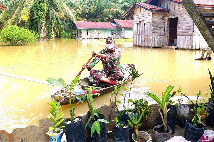 Seorang anggota TNI menggunakan perahu memantau warga yang dilanda banjir di Desa Sontang, Kecamatan Bonai Darussalam, Kabupaten Rokan Hulu, Riau, Kamis (26/11/2020).