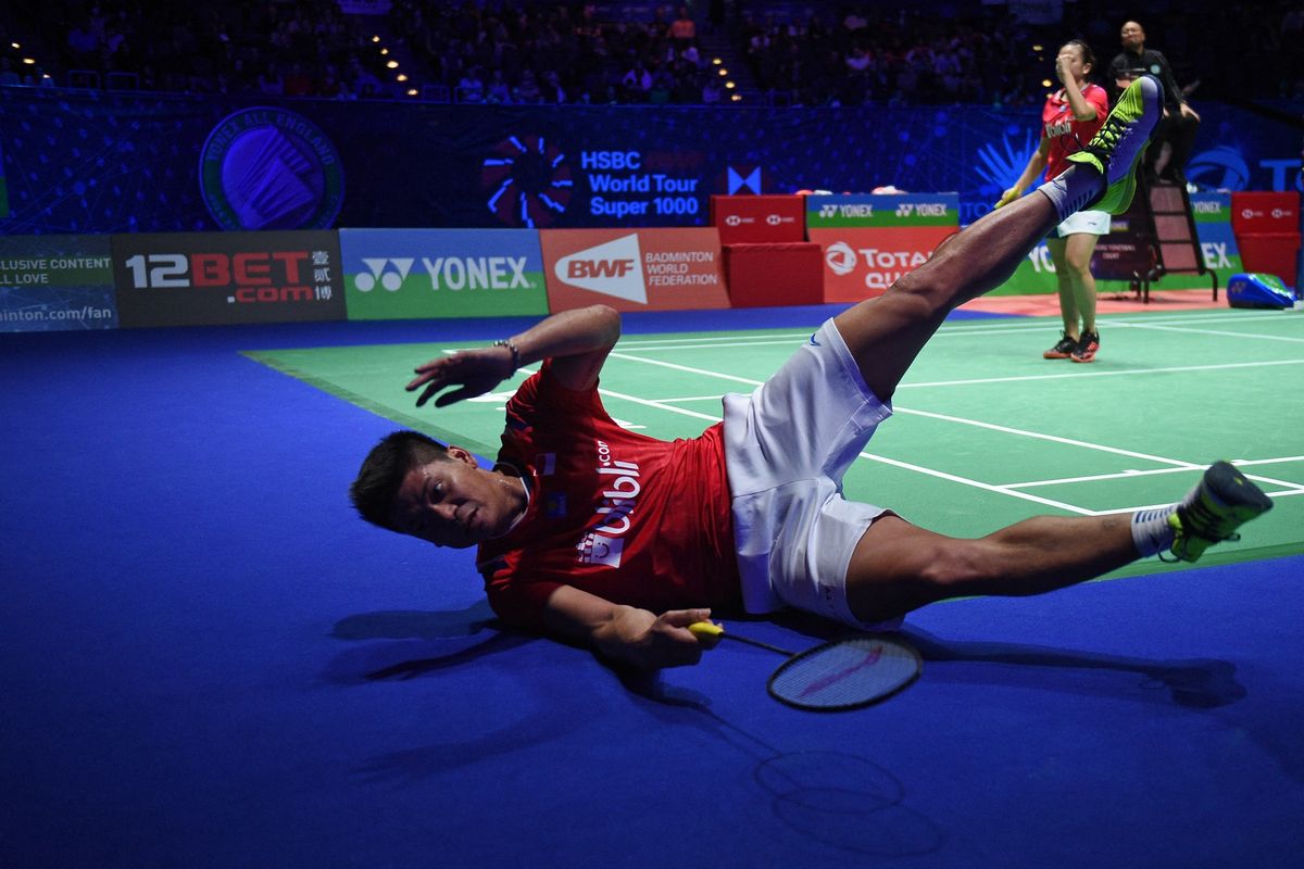 Indonesia's Praveen Jordan (L) playing with Indonesia's Melati Daeva Oktavianti stumbles as they play against Thailand's Dechapol Puavaranukroh and Sapsiree Taerattanachai  during their All England Open Badminton Championships mixed doubles final match in Birmingham, central England, on March 15, 2020. (Photo by Oli SCARFF / AFP)