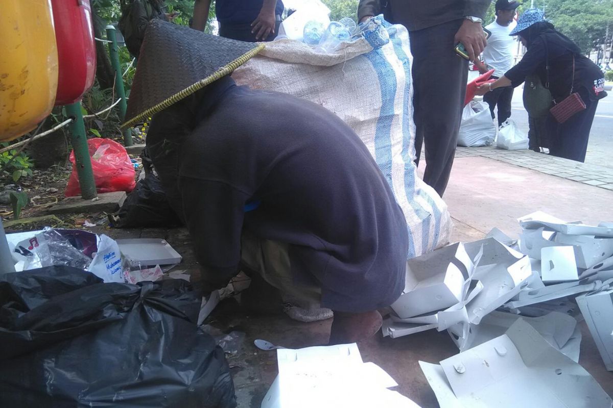 Bejo (60) terlihat sedang mencari dan memisahkan barang bekas di area monas