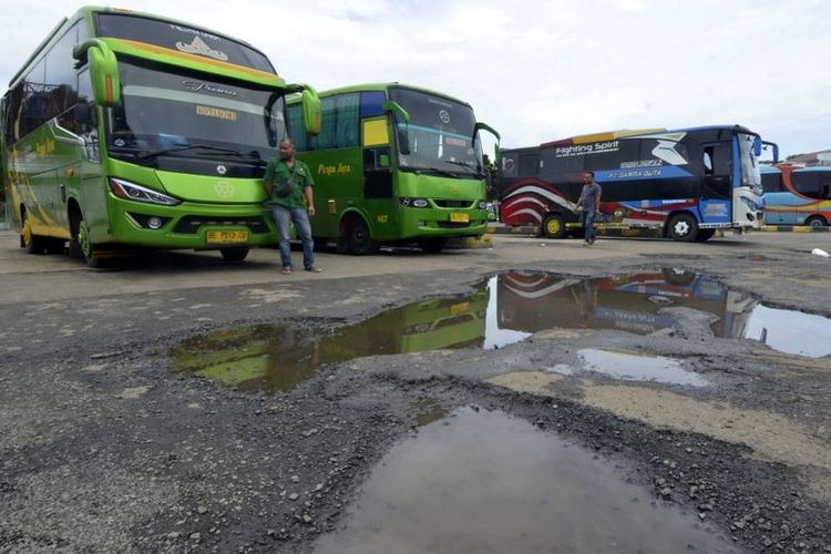 Sejumlah awak angkutan umum menunggu penumpang di dekat jalan yang rusak dan tergenang air di Terminal Rajabasa, Bandar Lampung, Lampung, Sabtu (1/4/2023).