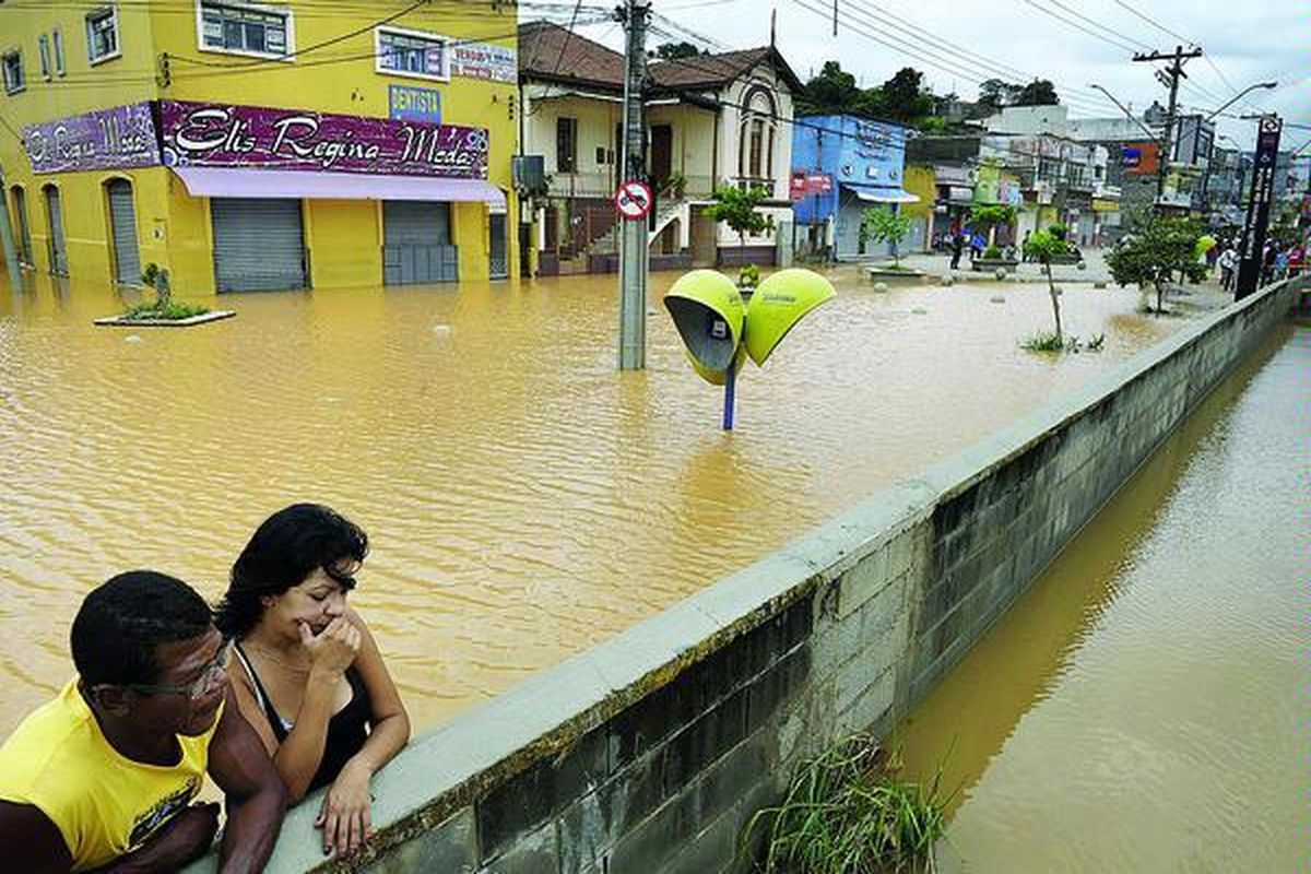 Warga mengamati banjir dari balik sebuah tembok di pusat kota Franco da Rocha, sekitar 35 kilometer sebelah barat Sao Paulo, Brasil, Rabu (12/1). Sepekan ini sebagian wilayah di Brasil dilanda hujan deras. Akibatnya lereng-lereng bukit, yang banyak dihuni warga, menjadi rapuh dan menimbulkan longsor mematikan.