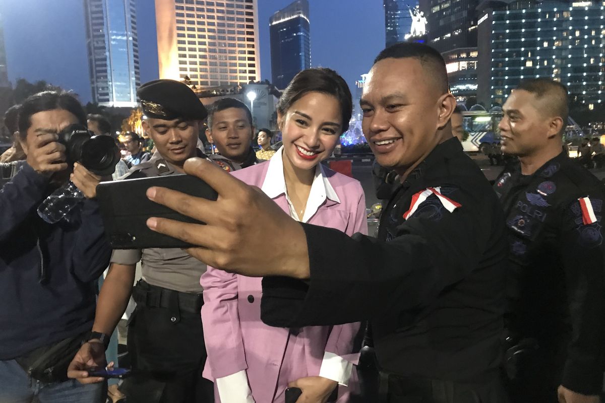 Artis seni peran sekaligus Wakil Direktur Penggalangan Pemilih Muda TKN Jokowi-Maruf Kirana Larasati selfie bersama anggota Brimob di Bundaran HI, Jumat (24/5/2019).