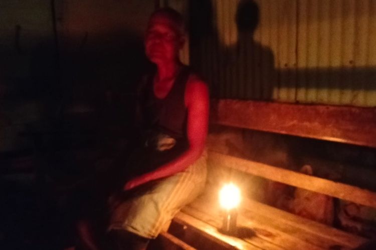 Zulkifli (62) warga desa Blang Reuling, Kecamatan Sawang, Kabupaten Aceh Utara sedang duduk di samping pelita karena kondisi listrik mati di Aceh.
