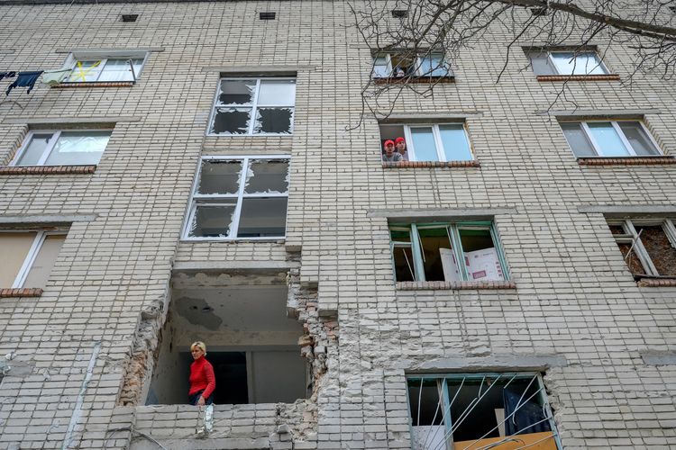 Seorang perempuan Ukraina menengok ke luar dari bangunan yang hancur terkena mortar Rusia di Mykolaiv, 100 km jaraknya dari Odessa di Ukraina barat, Selasa (8/3/2022).