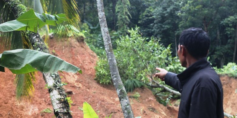 Seorang warga memerlihatkan sisa longsoran di lereng bukit yang menerjang puluhan rumah hingga ambruk, dan belasan lainnya rusak.