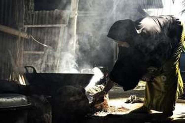 Seorang wanita di Desa Reksonegoro, Gorontalo, memasak dengan menggunakan tungku api. Umumnya mereka memiiki pekerjaan sebagai petani atau pedagang.