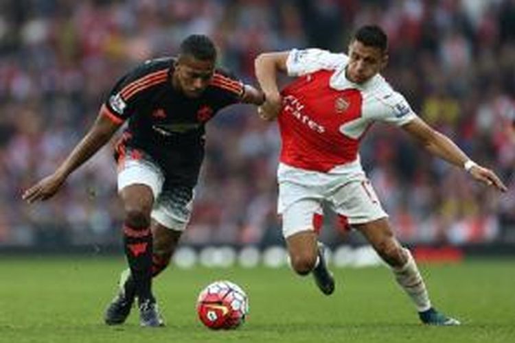 Penyerang Arsenal, Alexis Sanchez (kanan), tengah berebut bola dengan gelandang Manchester United, Antonio Valencia, pada laga Premier League di Stadion Emirates, Minggu (4/10/2015). 