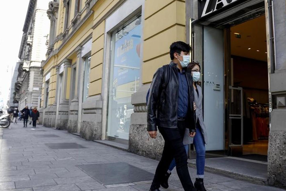 Seorang pria dan wanita berjalan memakai masker di depan gerai ZARA di Corso Buenos Aires, sebuah jalan yang berisi banyak toko-toko ternama di Milan, Italia. Foto diambil pada 10 Maret 2020.