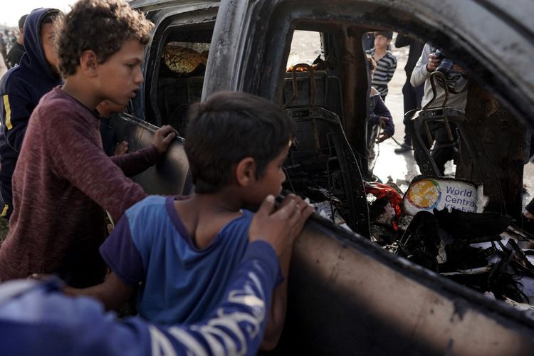 Orang-orang berkumpul di sekitar mobil yang digunakan oleh kelompok bantuan World Central Kitchen yang berbasis di AS, yang terkena serangan Israel sehari sebelumnya di Deir al-Balah di Jalur Gaza tengah pada 2 April 2024.