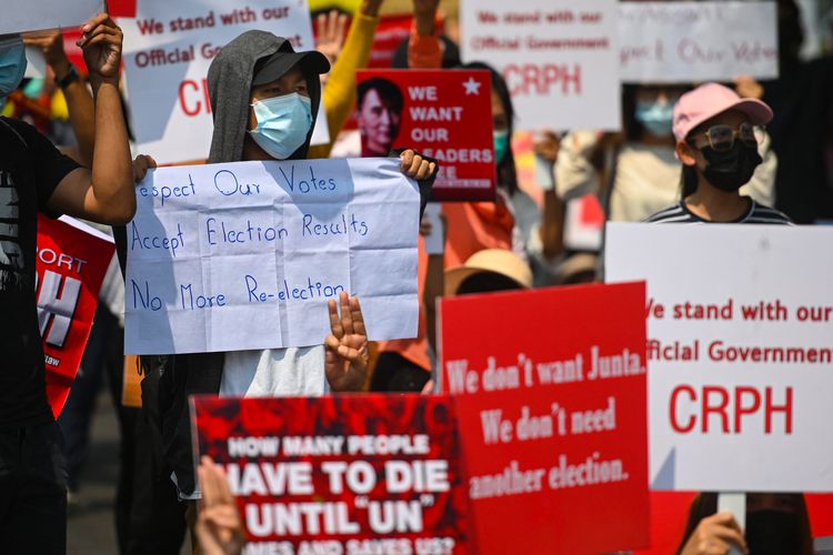 Para pengunjuk rasa memegang papan demo saat mereka melakukan demonstrasi menentang kudeta militer di depan Kedutaan Besar Indonesia di Yangon pada 23 Februari 2021. [Sai Aung Main/AFP]