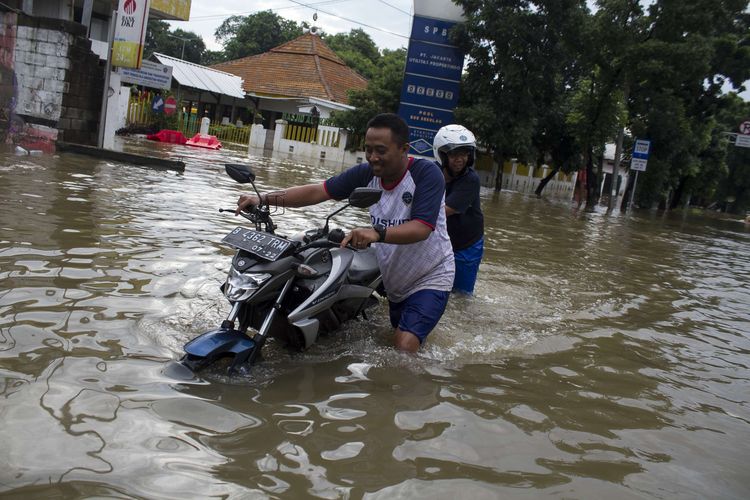 Sejumlah warga mengevakuasi sepeda motor yang terendam banjir di Jl. Raya Pondok Gede, Kramat Jati, Jakarta Timur, Rabu (1/1/2020). Luapan air Kali Baru sebabkan wilayah Kramat Jati terendam hingga sebahu orang dewasa.