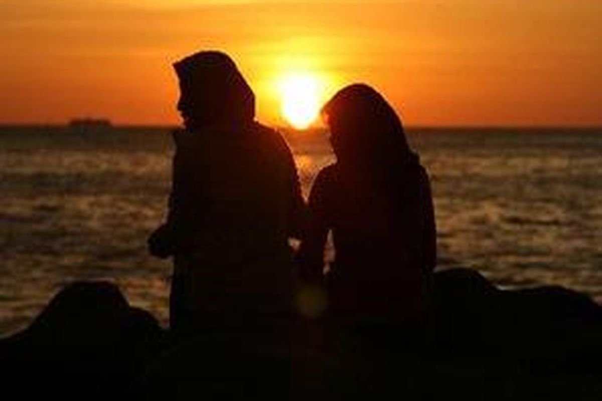 Dua perempuan menikmati keindahan alam saat matahari menjelang terbenam di Pantai Padang, Sumatera Barat. Pantai yang terletak kurang dari dua kilometer dari pusat kota itu menjadi tempat favorit untuk merintang waktu di sore hari.