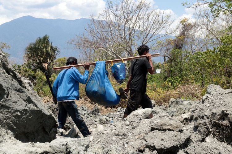 Dua orang warga Petobo mengevakuasi harta benda yang bisa diselamatkan setelah lumpur menggelamkan permukiman mereka
