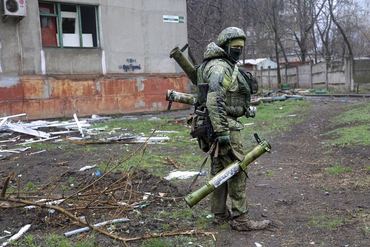FILE - Seorang prajurit bersenjata milisi Republik Rakyat Donetsk berjalan melewati sebuah bangunan yang rusak selama pertempuran di Mariupol, di wilayah yang sekarang berada di bawah kendali Pemerintah Republik Rakyat Donetsk, timur di Mariupol, Ukraina, Rabu, 13 April 2022. 