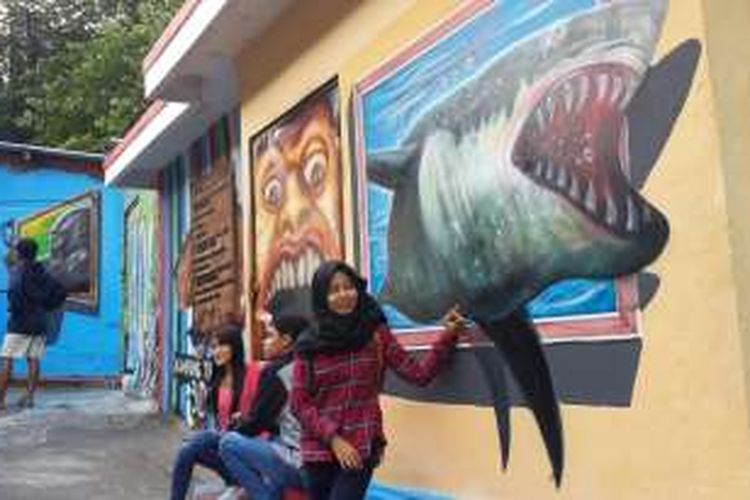 Sejumlah pengunjung saat berfoto di depan lukisan tiga dimensi di Kampung Tridi, Kelurahan Kesatrian, Kota Malang, Jawa Timur, Minggu (21/8/2016)
