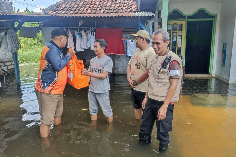 Plt Kepala BPBD Gresik Suyono (kiri), saat menyalurkan bantuan kepada warga yang terdampak banjir di Gresik, Jawa Timur, Minggu (11/2/2024).
