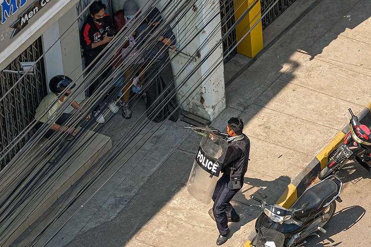 Seorang polisi mengarahkan senjatanya ke orang-orang di Taunggyi, sebuah kota di Negara Bagian Shan, Myanmar, ketika pasukan keamanan terus menindak demonstran yang menentang kudeta militer, Minggu (28/2/2021). Sedikitnya 18 orang tewas dan 30 lainnya terluka dalam aksi demonstrasi di Myanmar pada 28 Februari, serta disebut sebagai hari paling berdarah dalam serentetan aksi protes menentang kudeta militer.