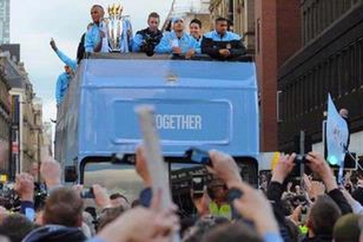 Kapten sekaligus bek Manchester City dari Belgia, Vincent Kompany (kiri), mengangkat trofi Juara Premier League 2012 saat parade kemenangan timnya mengelilingi pusat kota Manchester, Senin (14/5/2012).