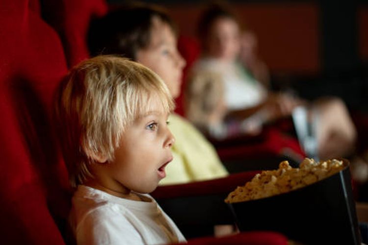 Ilustrasi anak kecil menonton film di bioskop.